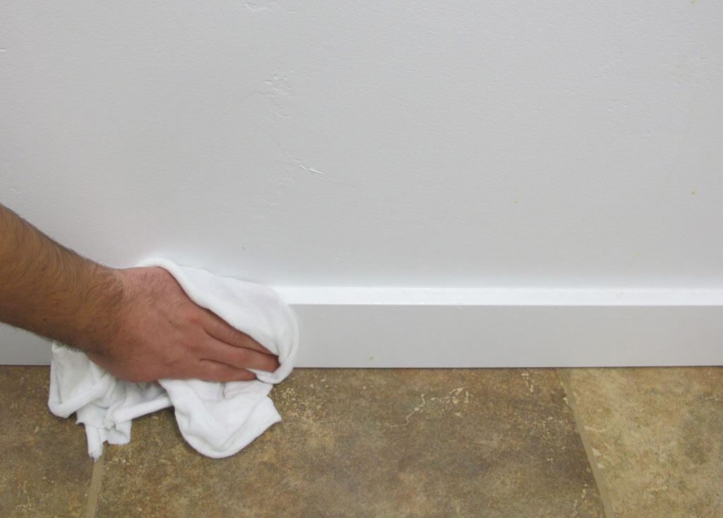 Wiping down a baseboard. 1024x734 - Dust & Debris: The Invisible Threats Of Your DIY Workspace